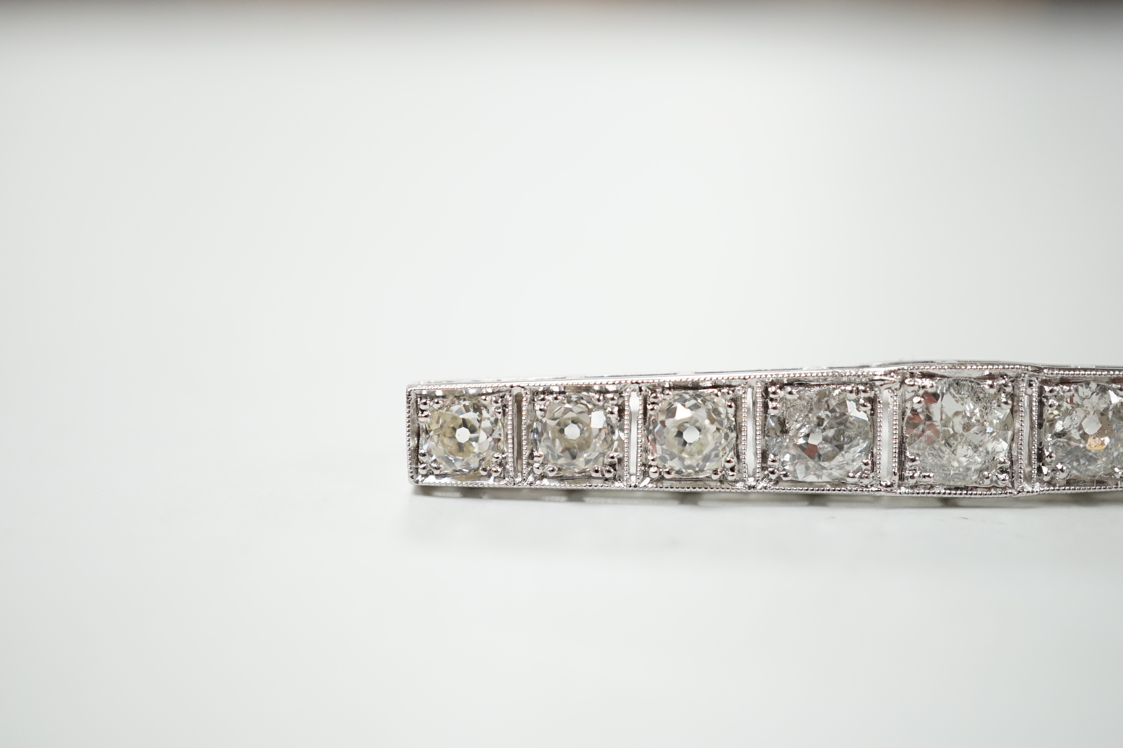 A 1920's/1930's white metal and graduated nine stone diamond set bar brooch, 48mm, gross weight 4.6 grams.